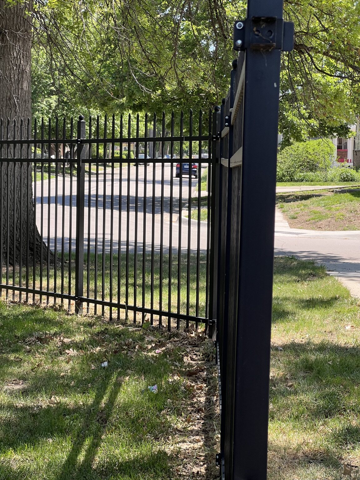 Close view of a black decorative steel walk gate with ball post caps