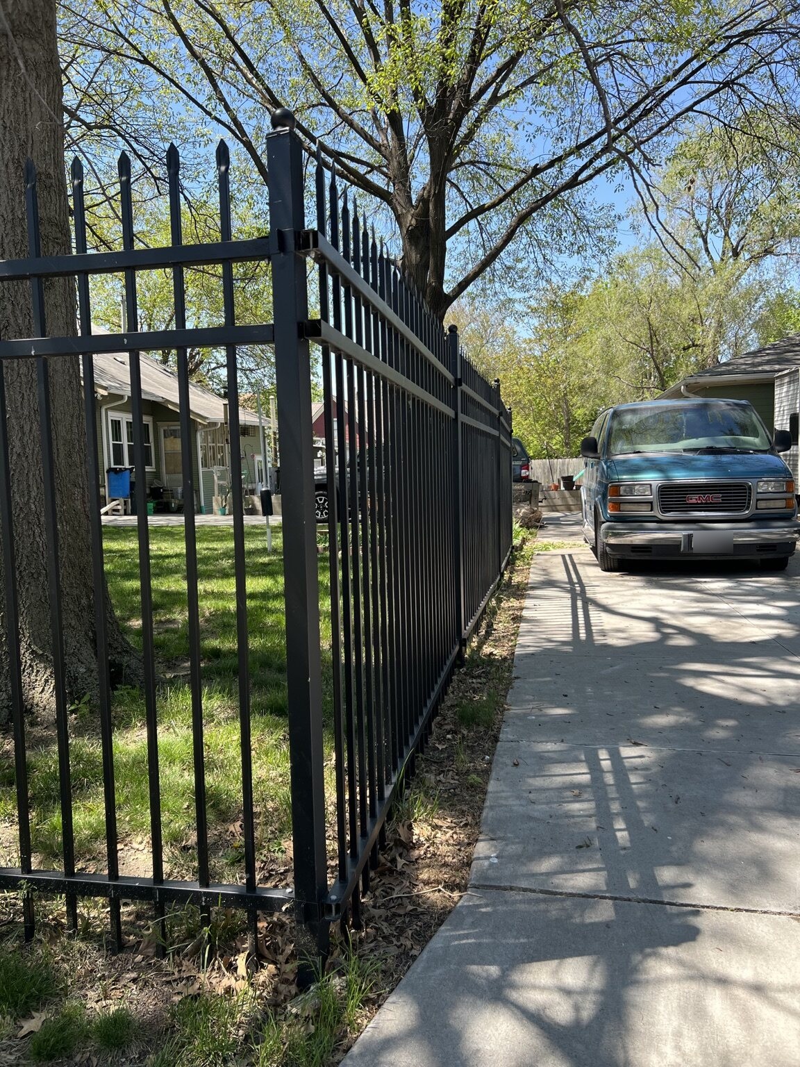 Black decorative steel fence and walk gate beside a residential driveway